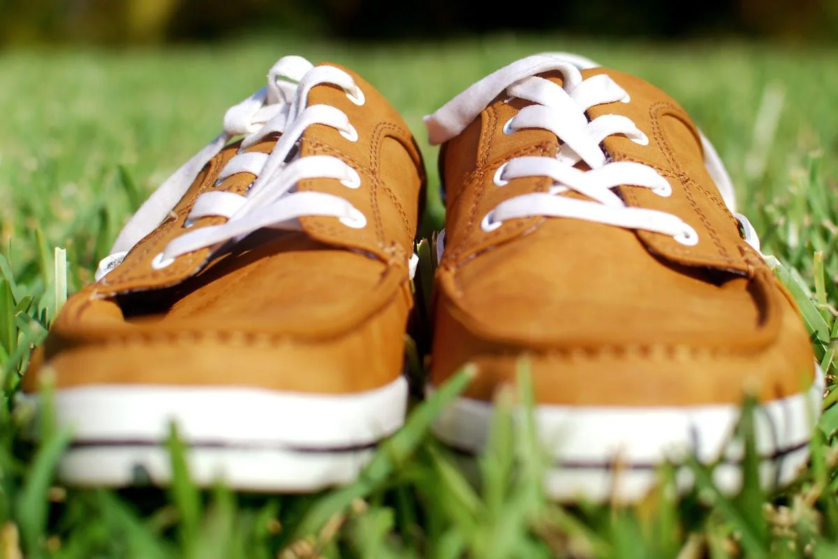 Chaussures de marin en cuir marron posées sur l'herbe verte.