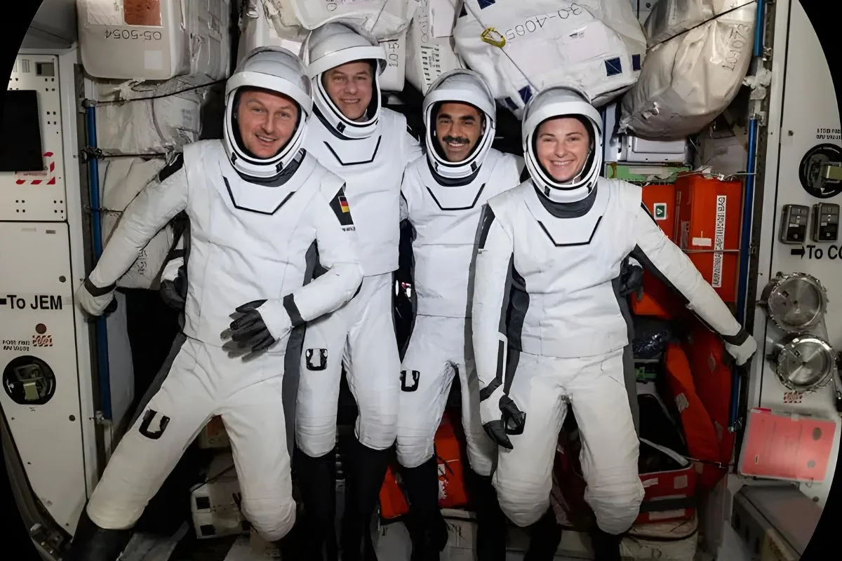 Quatre astronautes en combinaisons spatiales conçues par Prada en partenariat avec la NASA à bord d'une station spatiale.