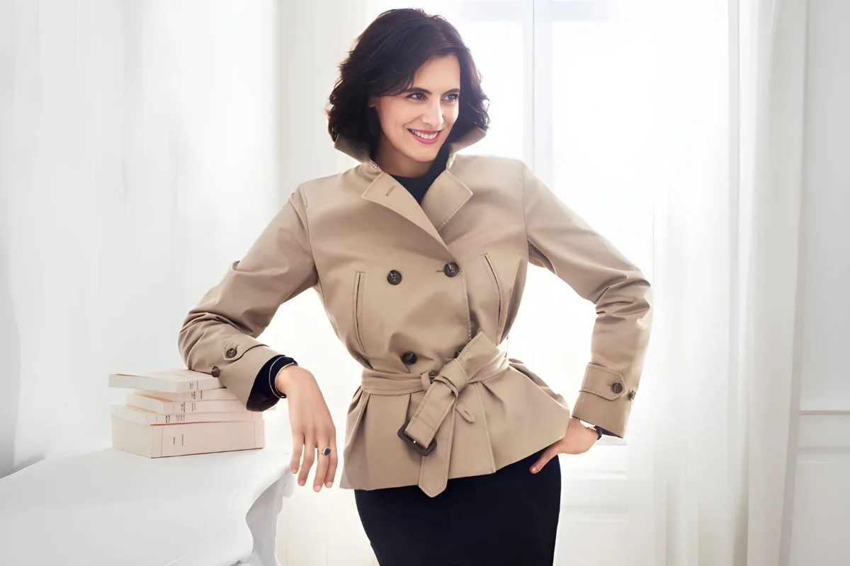 Inès de la Fressange pose avec élégance dans un trench-coat beige cintré.