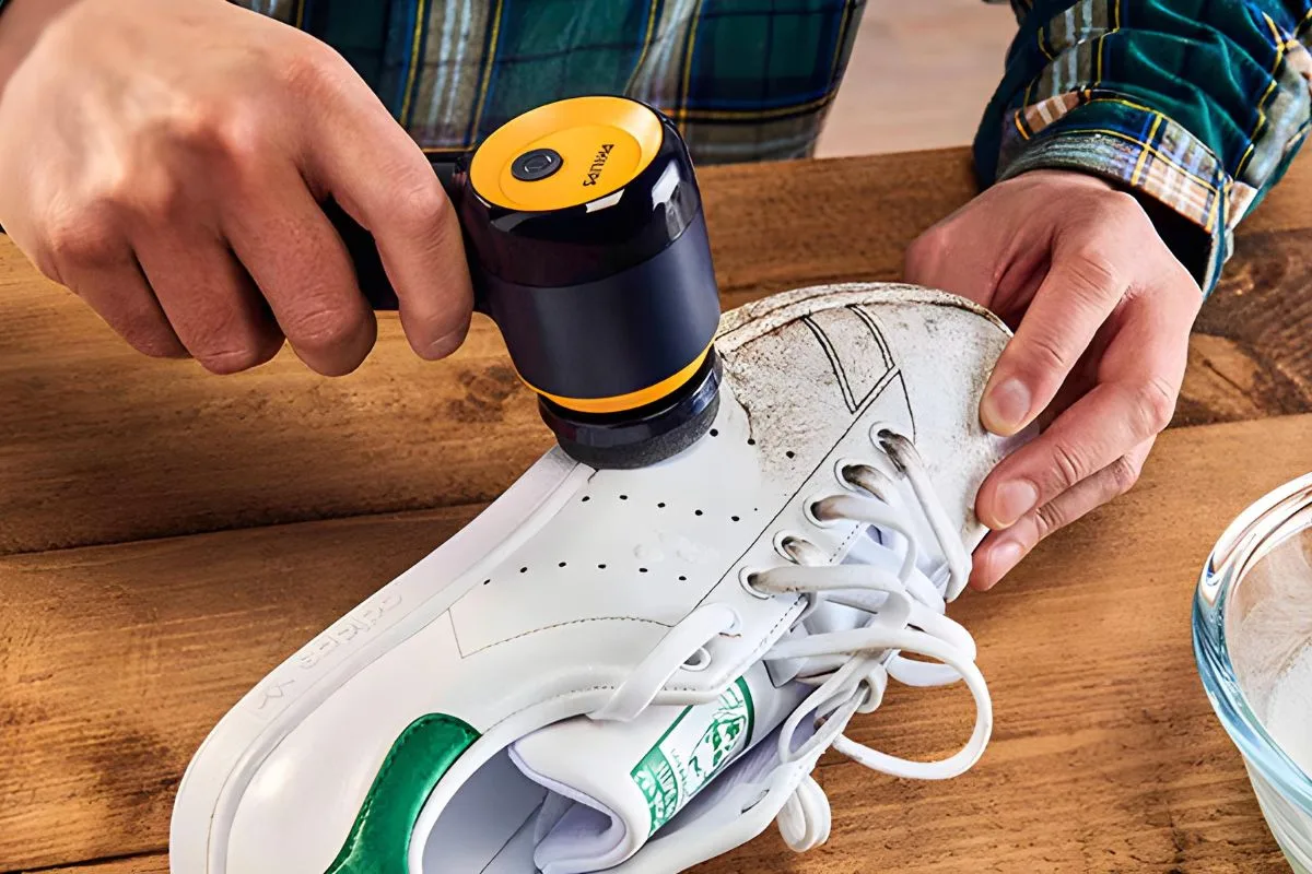 Mains utilisant le Philips Sneaker Cleaner sur une basket blanche sale pour démontrer son efficacité.