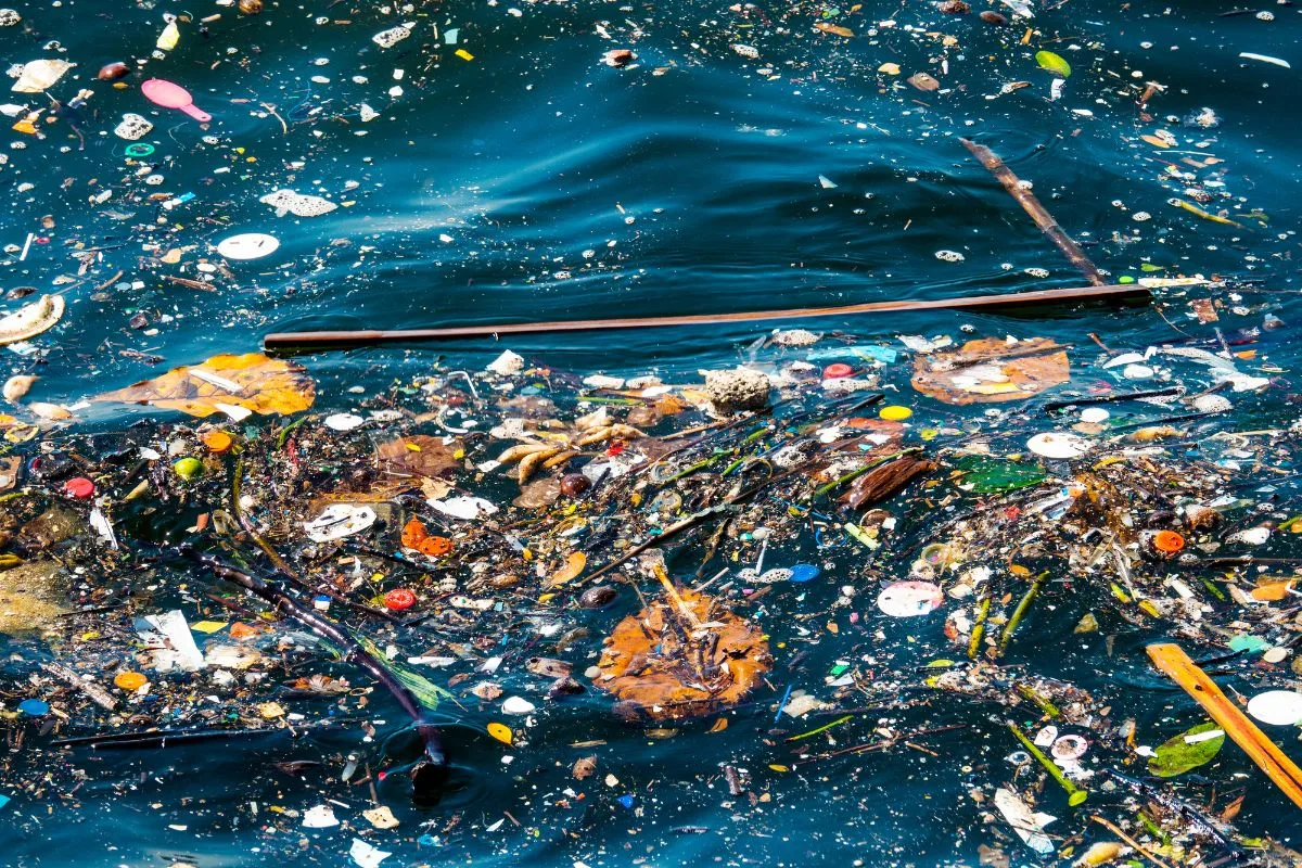 Eaux polluées avec des débris flottants, représentant l'impact environnemental de l'industrie textile.