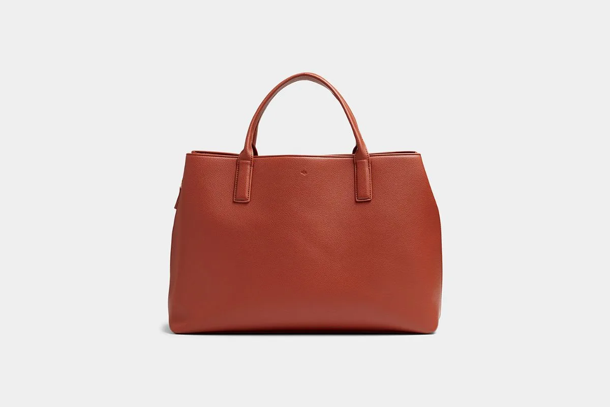 Sac à main fourre-tout en cuir marron terracotta avec une forme structurée sur un fond uni.