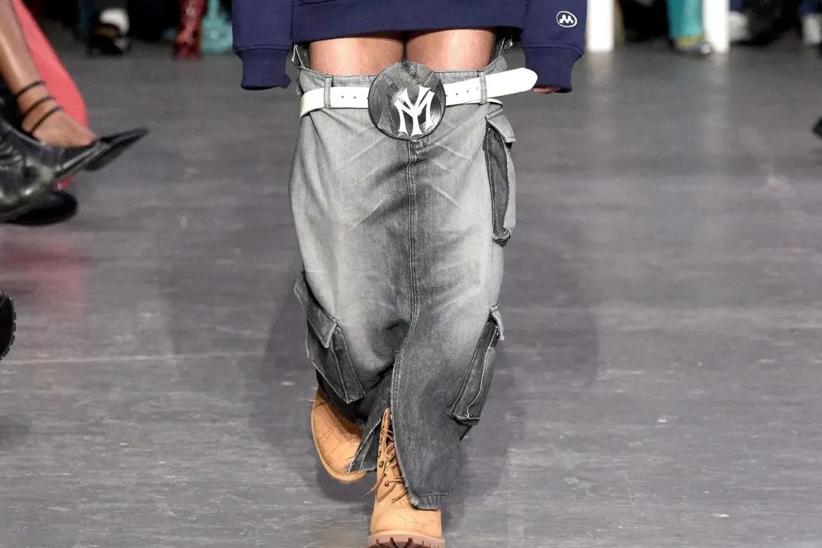 Modèle défilant avec un jean gris descendu sous la hanche