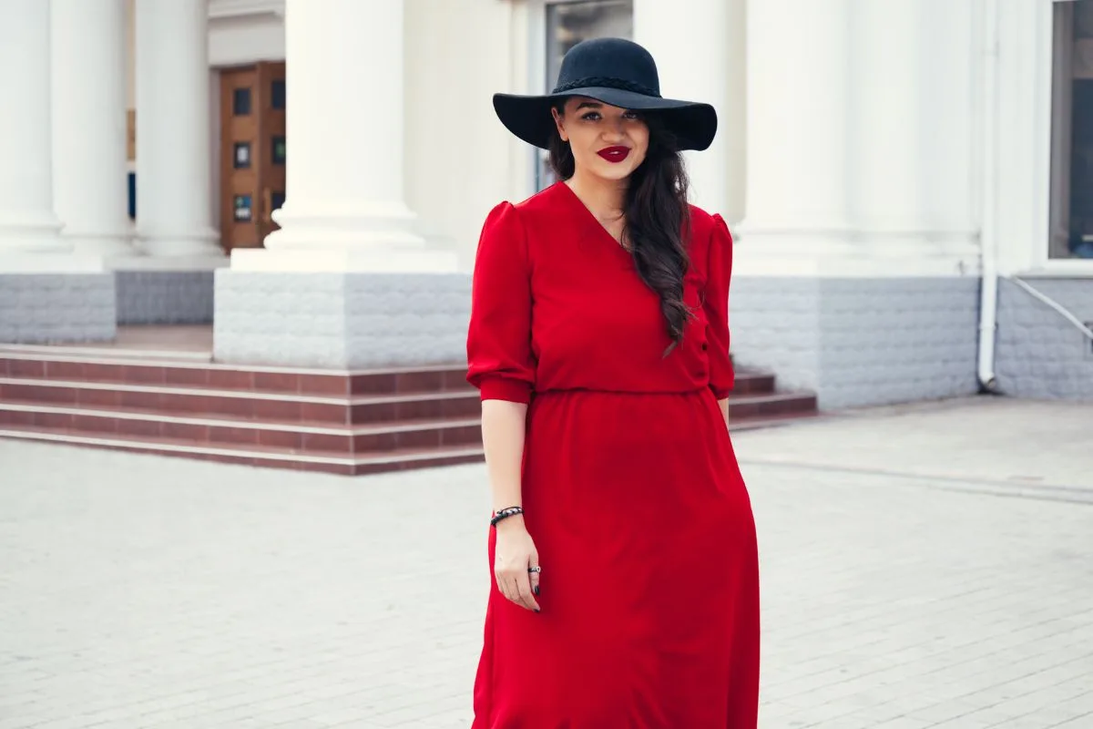 Femme en robe rouge vif et chapeau noir