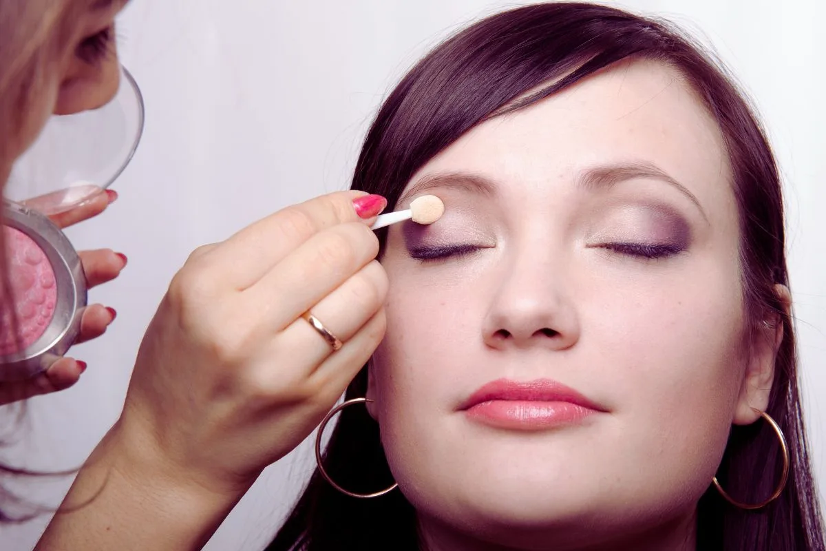 Makeup : Une femme se fait appliquer du fard à paupières pour un regard agrandi.